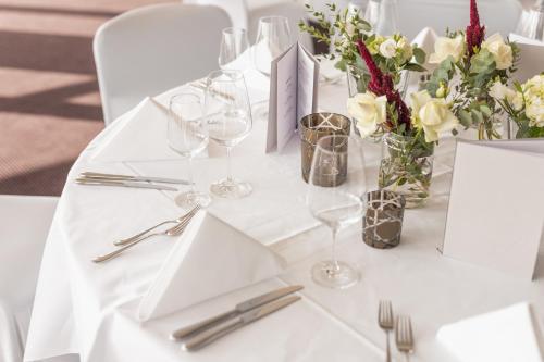 a white table with wine glasses and flowers on it at Parkhotel Heilbronn in Heilbronn