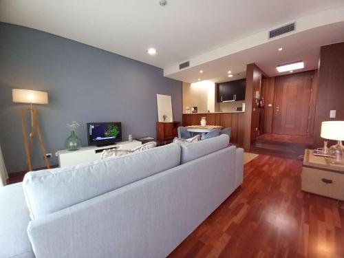 a living room with a white couch and a tv at Cabedelo Beach Apartment in Viana do Castelo