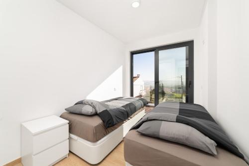 two beds in a white room with a window at Casa do Sol - By SCH in Salir de Porto