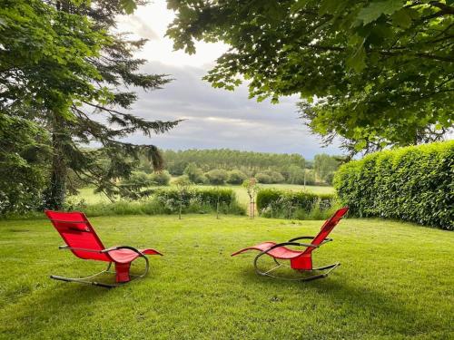 two red chairs sitting in a field of grass at Spacious country house in Normandie in Moulins-le-Carbonnel