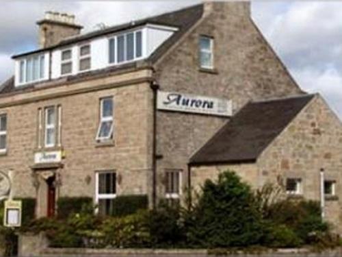 un gran edificio de ladrillo con un cartel. en Aurora Hotel & Italian Restaurant, en Nairn