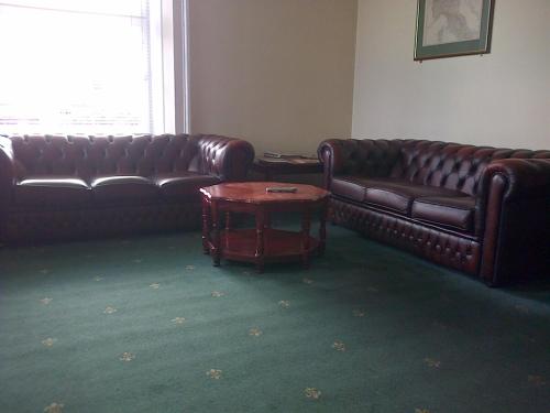 a living room with two leather couches and a coffee table at Aurora Hotel & Italian Restaurant in Nairn