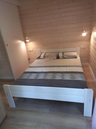 a white bed in a small room with wooden walls at Domek letniskowy Ostróda Arizona in Ostróda