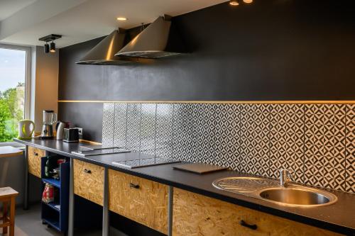 a kitchen with a sink and a black wall at Liepu Hostelis in Liepāja