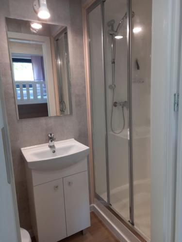 W łazience znajduje się biała umywalka i prysznic. w obiekcie Domek letniskowy Ostróda Arizona w Ostródzie