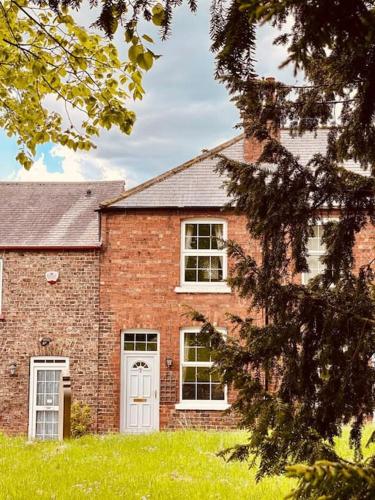 a brick house with a white door and windows at Church View, dog friendly, with parking, in Bolton Percy