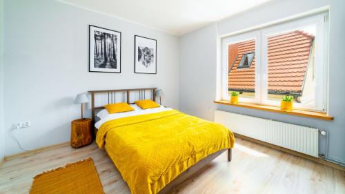 ein Schlafzimmer mit einem Bett mit gelber Bettwäsche und einem Fenster in der Unterkunft Apartament "Nad Jedlicą" in Kowary