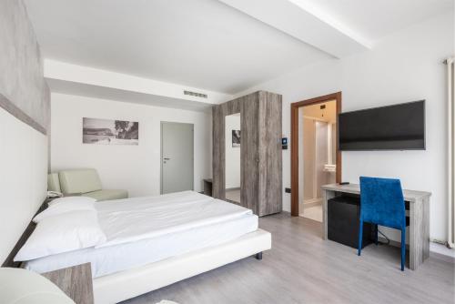 a bedroom with a bed and a desk and a tv at Hotel De Nac in Nago-Torbole