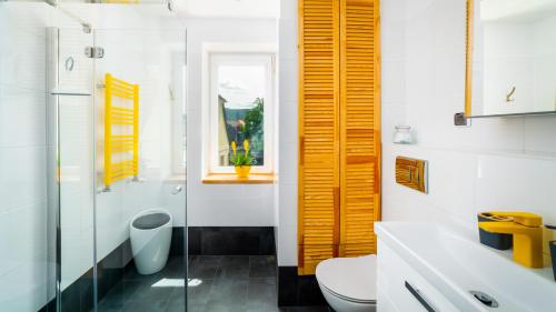 a bathroom with yellow shutters and a toilet at Apartament "Nad Jedlicą" in Kowary