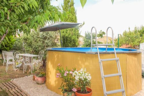 a hot tub in a backyard with an umbrella and a ladder at Alojamiento Rural El Gomis in Confrides