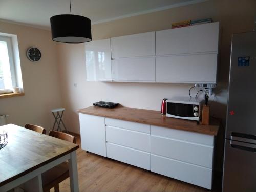 een keuken met witte kasten en een magnetron op een aanrecht bij Wygodny apartament blisko morza in Łokciowe