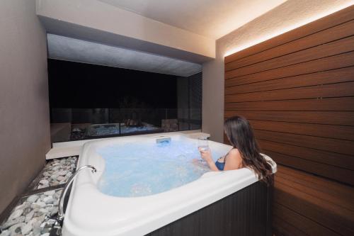 a woman sitting in a bath tub with a glass of wine at The View Luxury Apartments Taormina in Taormina