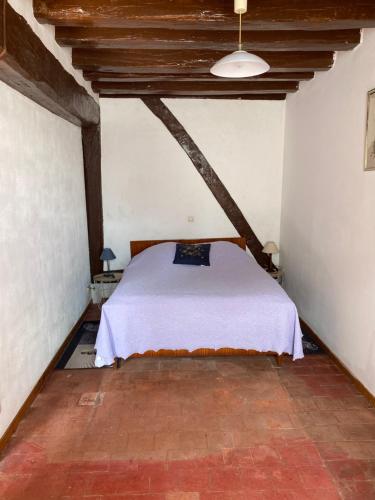 une chambre avec un lit dans le coin d'une pièce dans l'établissement Maison typique de sologne, à La Chapelle-dʼAngillon