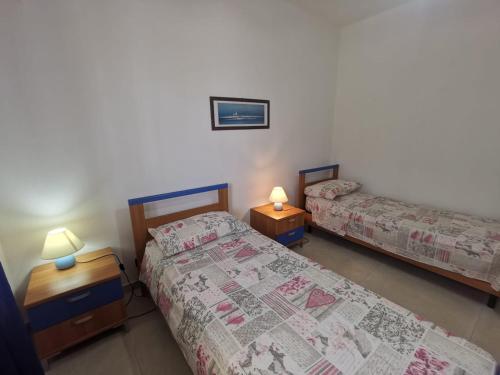 Habitación con 2 camas y 2 mesitas de noche con lámparas en Villetta a piano rialzato a 300 mt dal mare, en Marina di Pescoluse
