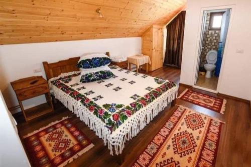 La Vasile la Cazan في Mara: غرفة نوم بسرير في غرفة بسقوف خشبية