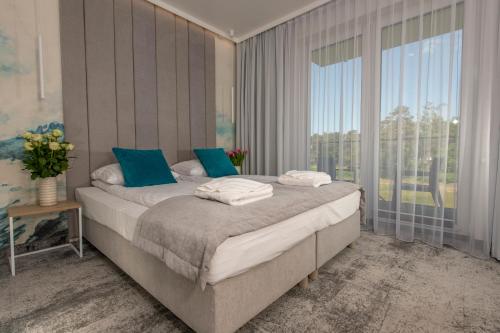 a bedroom with a bed with blue pillows and a window at Aquamarine Mielno in Mielno