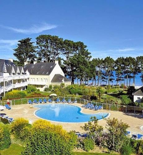 un complexe avec une piscine, des chaises et un bâtiment dans l'établissement FACE A LA MER, à Fouesnant