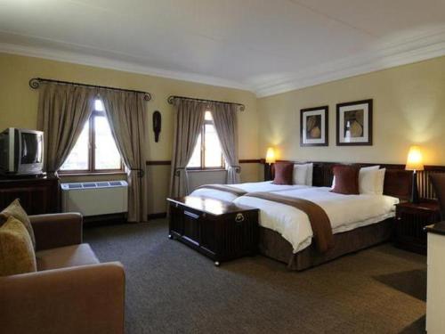 um quarto com uma cama grande e 2 janelas em Peermont Mondior Hotel em Gaborone