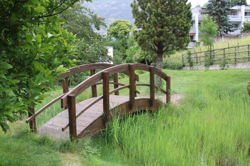 a wooden bridge in a field of tall grass at Hotel & Bildungshaus St. Jodern in Visp
