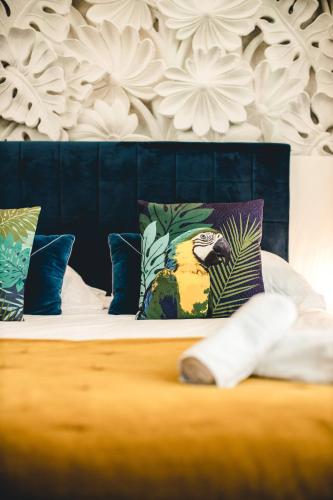 a bed with colorful pillows and a bird on it at Les Précieuses Suites & Spa I in Avignon