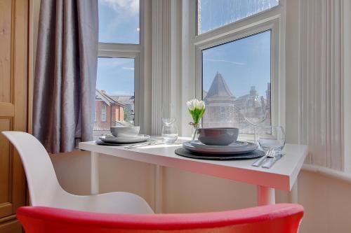 a table with plates and a red chair in front of a window at Heron Court Holiday Apartments in Bournemouth