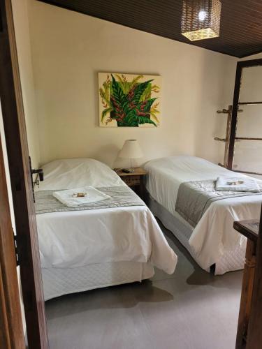 a bedroom with two beds and a picture on the wall at Gamboa Eco Refugio Pousada in Iporanga