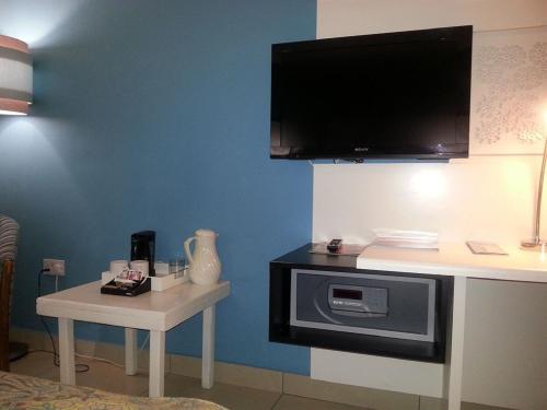 a room with a tv on a wall with a table at Peermont Metcourt Hotel in Francistown