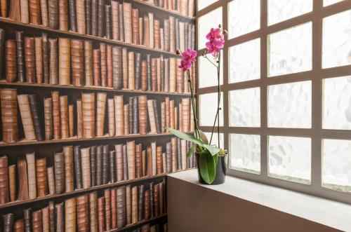 un jarrón con una flor en un estante en una biblioteca en Hôtel des Ecrivains, en París