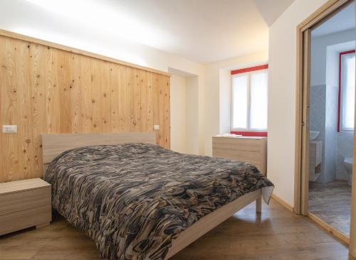 a bedroom with a bed and a wooden wall at La primula della Valle Soana in Ronco Canavese