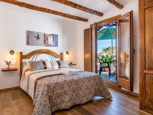 - une chambre avec un lit et une porte menant à une terrasse dans l'établissement Apartamentos Entre Senderos, à Capileira