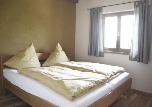 Cette chambre comprend un lit avec des draps blancs et une fenêtre. dans l'établissement Ferienhof Forstmoar, à Gars am Inn