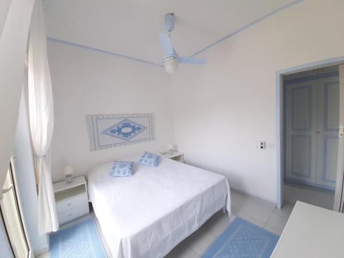 a white bedroom with a bed with blue pillows at Overlooking the sea Santa Teresa Gallura in Santa Teresa Gallura