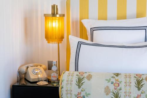 a bedroom with a bed with a phone on a night stand at Hôtel Le Y in Saint-Tropez