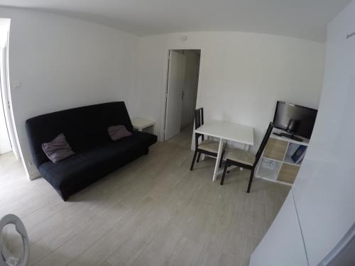 un salon avec un canapé noir et une table dans l'établissement Beau T2 neuf au calme entre mer et montagne, à Bassussarry