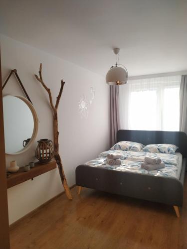 een slaapkamer met een bed met een spiegel en een raam bij Uroczy apartament nad morzem Gdańsk in Gdańsk