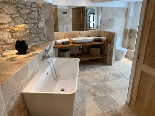 a bathroom with a white tub and a sink at Le Relais de Campagne in Tréjouls