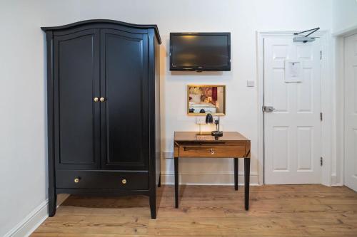 a black cabinet next to a desk and a tv at G Boutique Hotel in Portsmouth