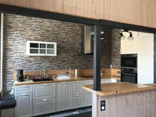 a kitchen with white cabinets and a brick wall at L'Oréline au cœur de la région des Lacs du Jura in Pont-de-Poitte