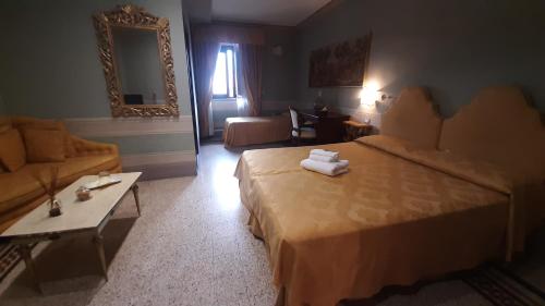 a hotel room with two beds and a table at I Portici Hotel - Residenza D'Epoca in Arezzo