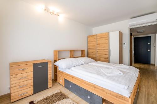 a bedroom with a wooden bed and a wooden dresser at MF SilverBeach 112 Apartment in Siófok