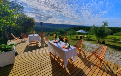 a wooden deck with two tables and chairs on it at Pousada Olival Vila do Segredo in Caçapava do Sul