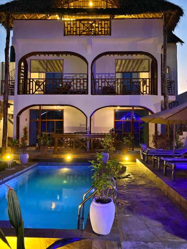 a villa with a swimming pool at night at Utulivu Bungalow in Nungwi