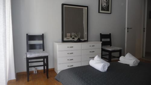 ein Schlafzimmer mit 2 Stühlen und eine Kommode mit einem Spiegel in der Unterkunft D&J Central Appartment in Ioannina