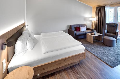 a bedroom with a large bed and a living room at Hotel Kühberg in Oberstdorf