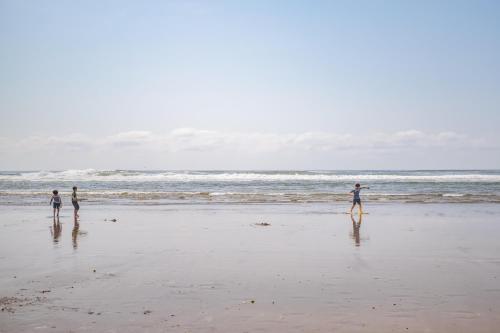 three people standing on a beach near the ocean at Beach Captain - Meredith Lodging in Neskowin