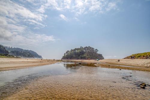 a beach with a body of water and people on it at Beach Captain - Meredith Lodging in Neskowin