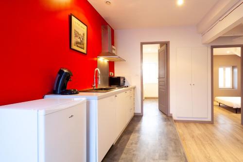 a kitchen with red walls and a white counter top at Le Grande Moderno in Angoulême