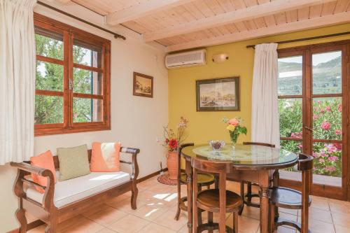 a living room with a table and chairs and windows at Therianos Traditional Villas in Kallithea