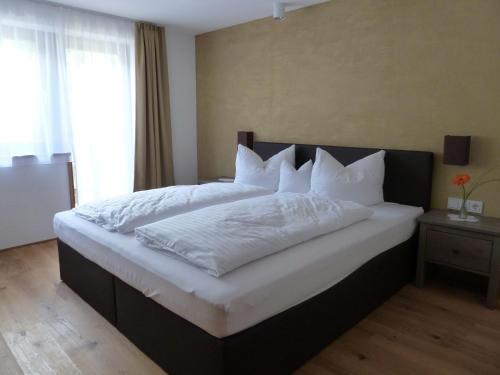 una camera da letto con un grande letto con lenzuola e cuscini bianchi di Apartments Bischof a Schröcken
