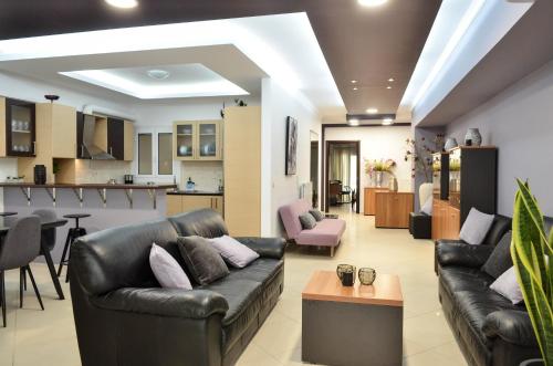 uma sala de estar com mobiliário de couro preto e uma cozinha em Feve's Apartment em Kalamata
